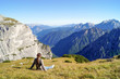 © kapichka - girl sits on the grass and admires the beautiful mountain view in the Alps