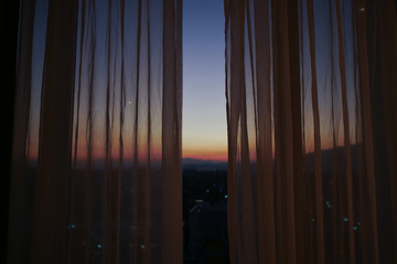 Wall Mural - sunlight through curtain with twilight sunset sky view outside the window