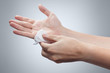 Two hands wiping each other with a wet napkin on gray background