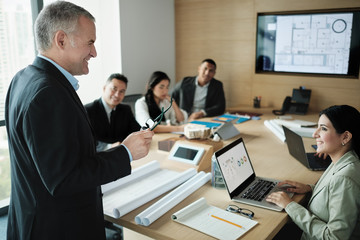 Architect Showing Miniature Building At Business Meeting With Client