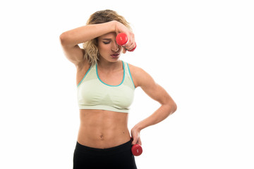 Wall Mural - Beautiful young fit girl looking tired holding dumbbells