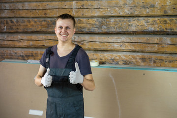 A young and cheerful man shows likes on a construction site.