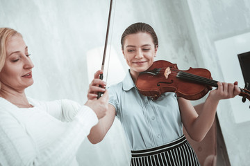 Wall Mural - Delighted joyful girl taking a violin bow