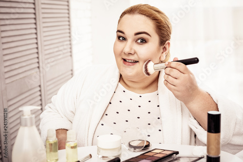 Foto Peaceful smiling woman using powder brush for putting makeup