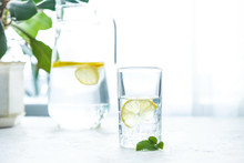 Glass Cup And A Carafe Of Water, Ice, Mint And Lemon On A White Table
