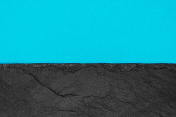 Abstract background composition of divided in the half matt vivid soft blue color paper and black stone with copy space