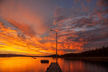 Wall Mural - sunset on the river. pier with light pole in the foreground.