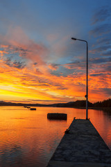 Wall Mural - sunset on the river. pier with light pole in the foreground.