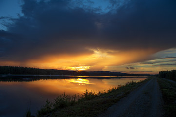 Wall Mural - sunset on the river. single lane road leading through landscape.