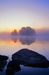 Wall Mural - early morning sunrise. small island in the mist.