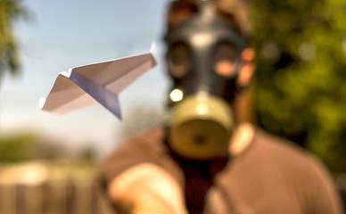 Throwing a paper airplane while wearing a gas mask