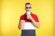 Man with 3D glasses, popcorn and beverage during cinema show on color background