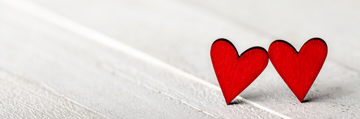 Wall Mural - two red valentine's day hearts standing on white wooden table