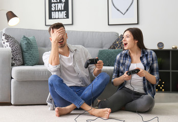 Wall Mural - Young couple playing video games at home