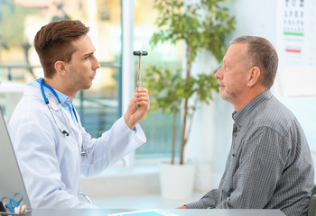 Sticker - Doctor checking reflexes of mature patient in hospital