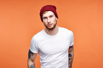 a man in a cap white t-shirt on an orange background logo