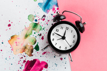 Wall Mural - Vintage alarm clock on a creative colorful background with paint sprinkles