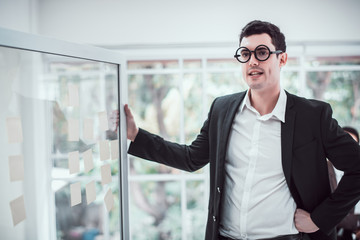 Young attractive businessman standing with board to present financial report at meeting. 