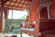 © astrosystem - Woman using laptop, cellphone and drinking coffee on a home porch in the summertime.