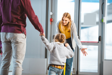 Wall Mural - selective focus of cheerful mother smiling to daughter in airport