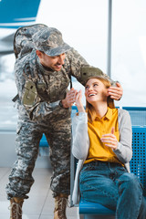 Wall Mural - cheerful veteran looking at surprised girlfriend in airport