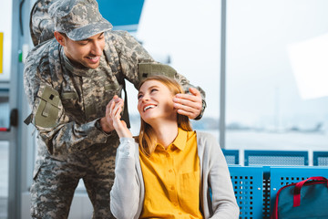 Wall Mural - handsome veteran looking at cheerful girlfriend in airport