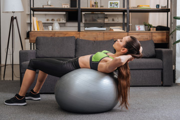 Wall Mural - focused sportswoman exercising with fitness ball at home