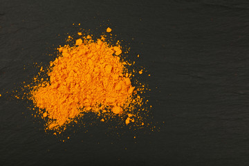 Wall Mural - Heap of yellow turmeric powder on black slate board