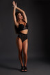 © nazarovsergey - Young sexy slim tanned woman in black underwear posing against dark grey background.