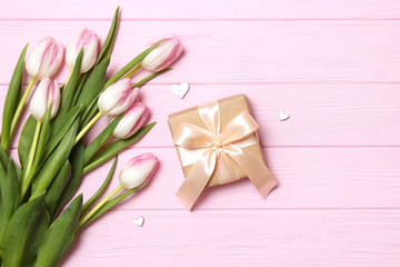 A bouquet of beautiful tulips and a gift on a wooden background top view. Mother's Day Background, International Women's Day. Holiday, give a gift.