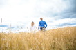 © FytyaKarman - couple girl and guy on the field with wheat look into the blue sky holding hands