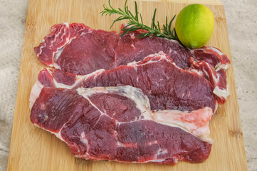 fresh beef meat on a cutting board with lemon and rosemary