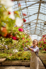 Wall Mural - Young woman working with spring flowers in the greenhouse