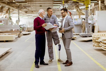 Wall Mural - Three men standing and discuss in furniture factory