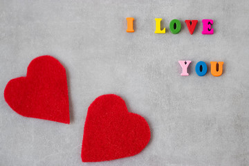 Multicolored letters and two red decorative hearts on gray background. I love you. Valentine's Day Concept.