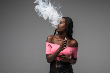 Young beauty african woman smoke vape, e-cigarette, isolated on gray background