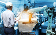 © sittinan - Man hand holding QC check with automate wireless Robot arm in smart factory background. Mixed media of welding robot in the automotive parts industry