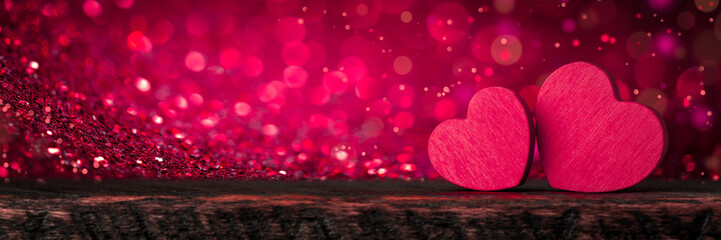 Wall Mural - two pink valentine's hearts standing on wooden table with soft romantic background