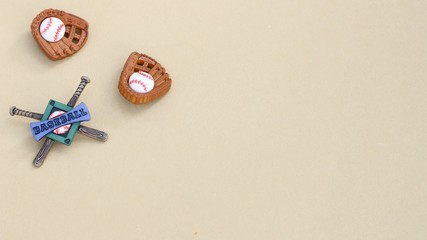 two baseball mitts and balls with baseball banner sign attached to bats laying flat on a tan background with writing space