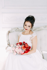 Wall Mural - Beautiful girl in a wedding dress with a bouquet. Bride in a bright Sunny Studio.