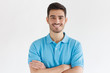 © Damir Khabirov - Smiling handsome man in blue polo shirt standing with crossed arms isolated on gray background