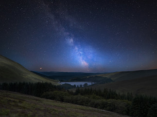 vibrant milky way composite image over landscape of mountains in distance