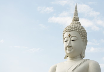 White Buddha statue on sky background.