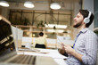 © pressmaster - Happy young businessman in headphones singing and listening to his favorite songs by workplace in office