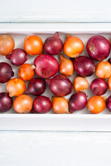 Wall Mural - onions on white wood tray, wooden table background