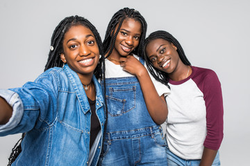 Wall Mural - Young pretty african women friends take selfie on the phone isolated on white background