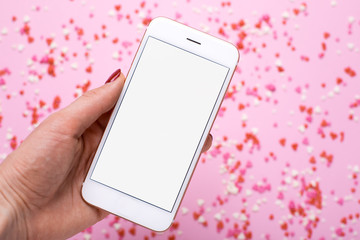 Female hand with mobile phone on background with pink and red hearts