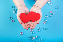Paper Red Double Heart In The Hands Of A Woman On A Blue Background And White Beads.