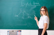 © Elnur - Young female english language teacher standing in front of the b