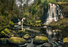 Long Exposure Shot Of Linn Jaw Waterfalls, Near Livingston, Scotland, With Mossy Rocks In The Foreground And Surrounding The Waterfalls And White Foam Streaks In The Water. West Lothian. UK. Nature. L